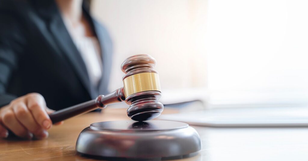 Closeup shot of a gavel with a woman in the background